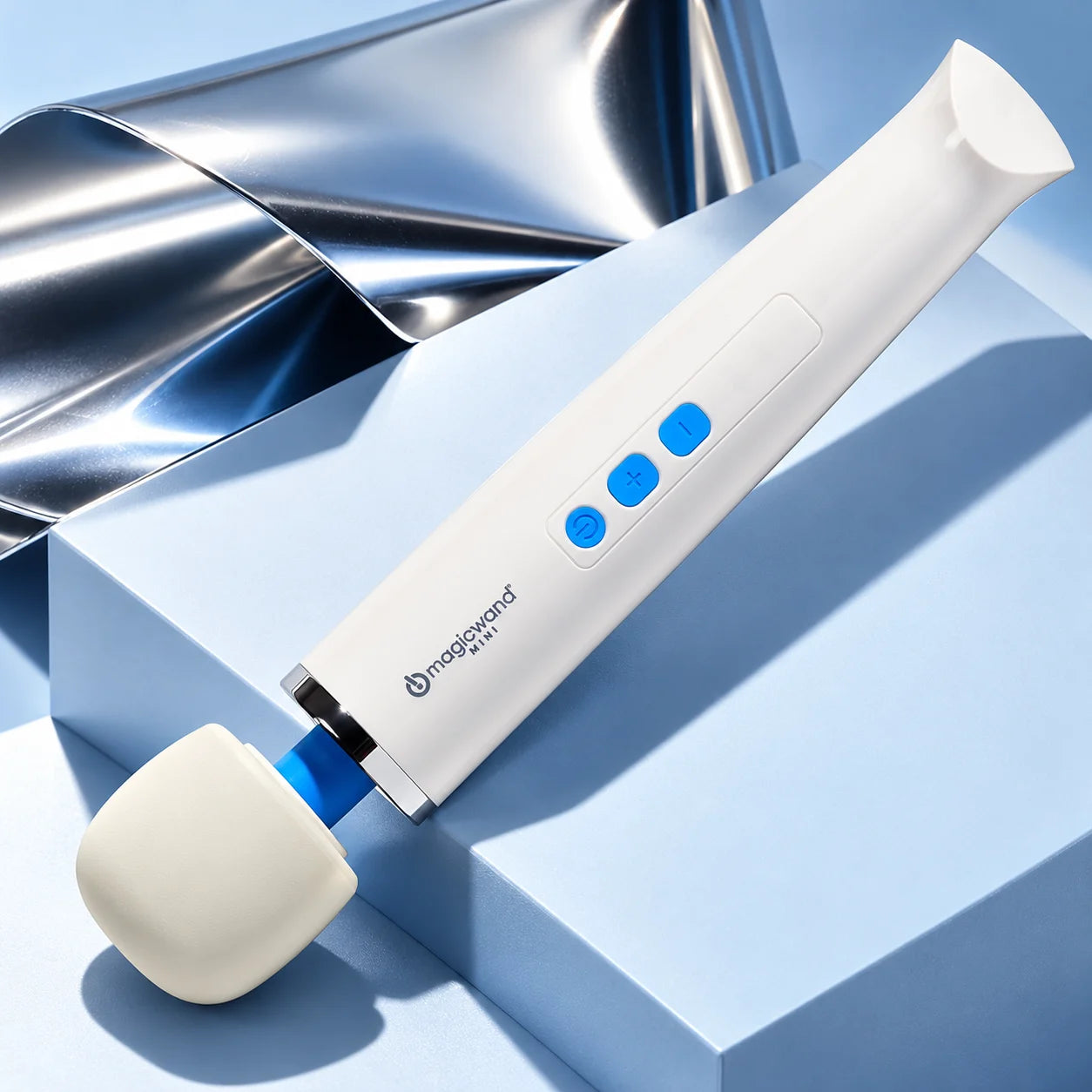 Magic Wand Mini on an icy-blue pedestal beside a folded chrome sheet.