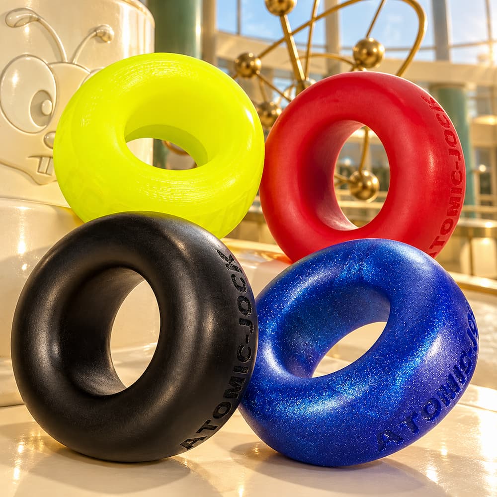 Five Oxballs Cock-T Atomic Jock silicone cockrings in assorted colors overlapping in a studio display
