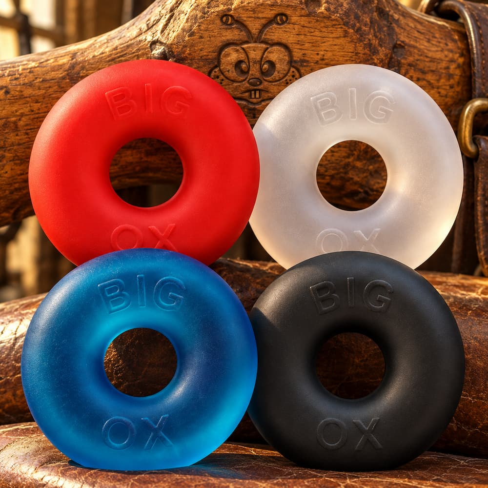 Four Oxballs Big Ox cockrings in red, blue, clear and black on a wooden surface