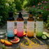 Four Sliquid Splash feminine washes with fruit and water in a garden setting
