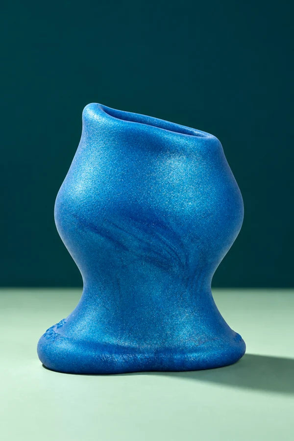Blue PIG HOLE hollow plug with shaped head, narrow neck and broad base on a mint surface.